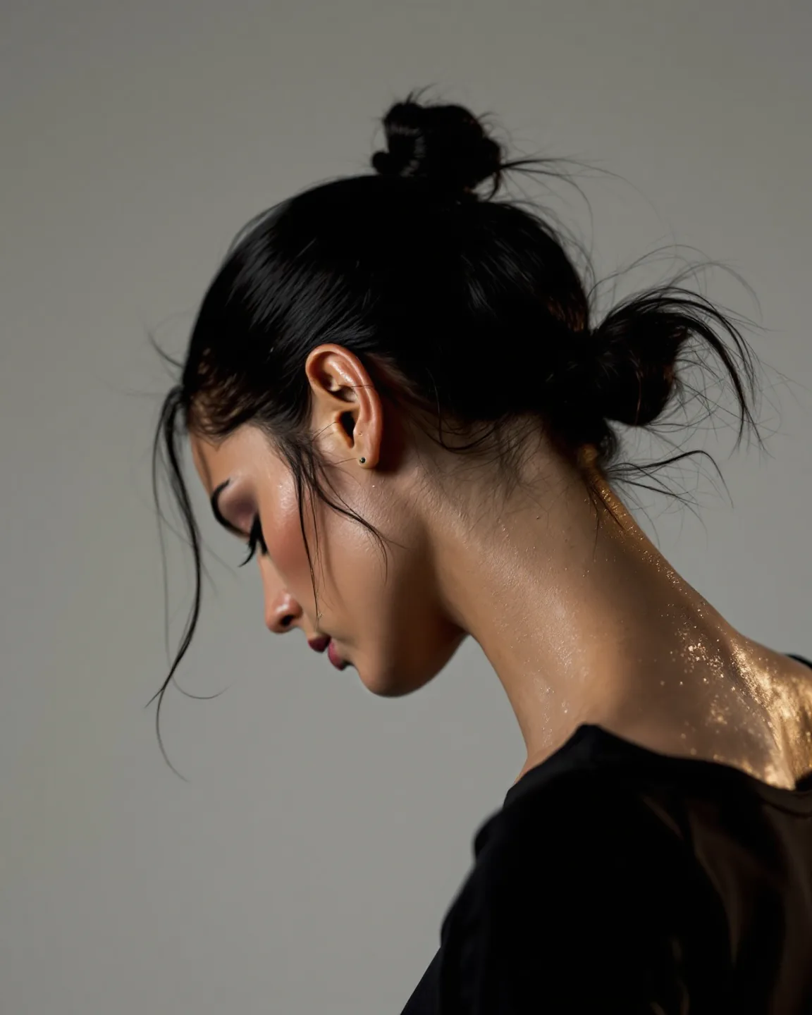 Sweat at the neck of a dancer with her hair pinned up, the black shirt sitting clean at the collar